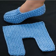 a pair of crocheted slippers sitting on top of a black surface next to a baby's foot