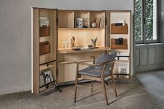 a chair sitting in front of a desk with shelves on the wall and an open bookcase