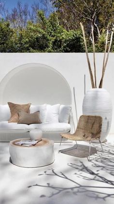 an outdoor living room with white furniture and trees