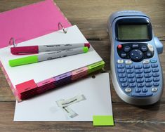 a calculator sitting on top of a wooden table next to notebooks and pens