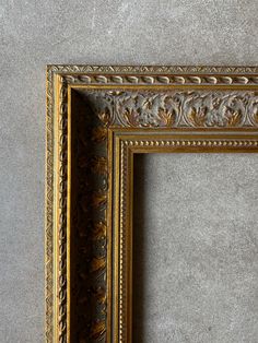 an ornate gold frame against a gray wall
