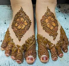 two feet with henna tattoos on them, one is showing it's intricate designs