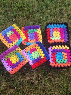 four square crocheted coasters sitting on the grass