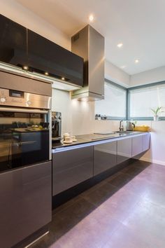 a modern kitchen with stainless steel appliances and counter tops, along with floor to ceiling windows