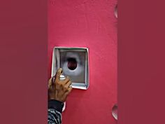 a hand is pressing the button on a red wall