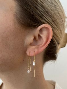 a close up of a person wearing gold earring with pearls on the end of it