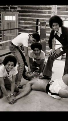 four young men are posing for a photo in an old boxing ring with one man laying on the ground