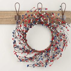 a wreath with red, white and blue beads hanging on a wooden wall hanger