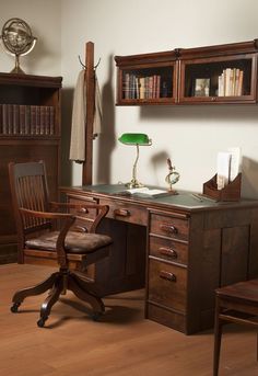 an old fashioned desk and chair in the corner of a room with bookshelves