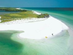 an island in the middle of the ocean with white sand and green grass on it