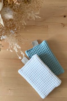 three pieces of cloth sitting on top of a wooden table next to a vase with dried flowers