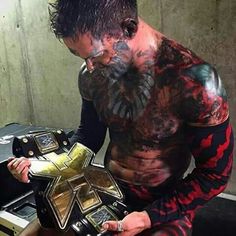 a man with tattoos on his body holding a wrestling belt and looking down at the camera