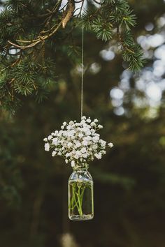 a mason jar filled with baby's breath flowers hanging from a tree