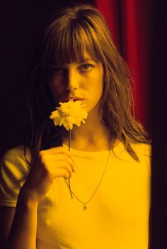 a woman holding a flower in front of her face