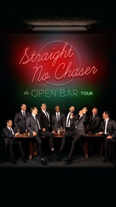 a group of men sitting at a table in front of a neon sign that says straight no chaser the open bar tour