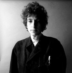 a black and white photo of a woman with curly hair, wearing a jacket and tie