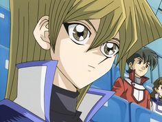 an anime character with blonde hair and big eyes looks at the camera while another person stands behind him