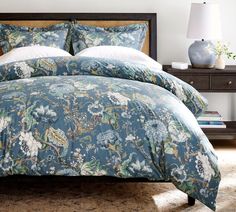a bed with blue floral comforter and pillows
