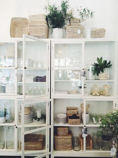 the shelves are filled with dishes and plants in glass containers on top of each shelf