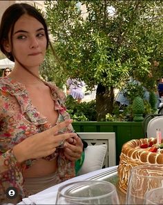 a woman standing in front of a cake with candles on it at an outdoor table