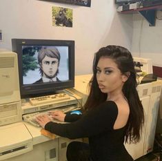 a woman sitting in front of a computer monitor