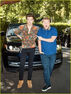 two men standing next to each other in front of a car