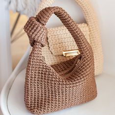 an image of a handbag that is sitting on a white chair with the handle down