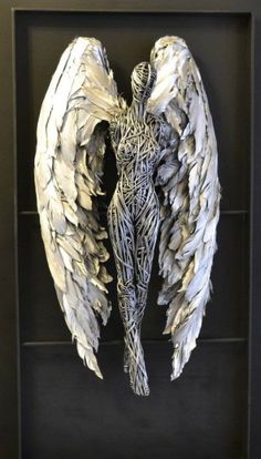 an angel sculpture with white wings in a black frame