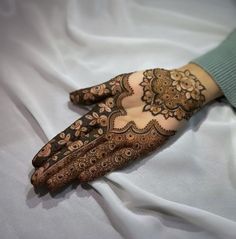 a woman's hand with henna on top of white sheeted bedding