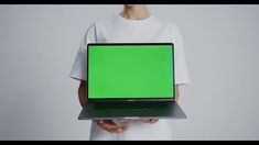 a person holding a laptop with a green screen