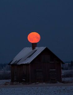 the full moon is setting over an old barn