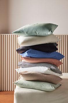 a stack of pillows sitting on top of a bed
