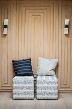 two white and blue pillows sitting next to each other on top of a wooden floor