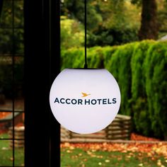 a hotel sign hanging from the ceiling in front of a lush green park with trees and bushes