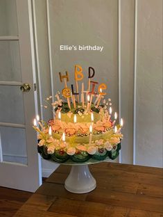 a birthday cake with lit candles sitting on a table in front of a door that says happy birthday