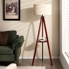 a living room with a green chair and a wooden floor lamp in front of a painting