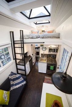 the interior of a tiny house with loft bed and kitchenette in white, wood flooring