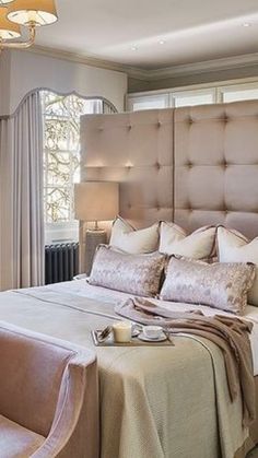 a bedroom with a bed, chair and chandelier in front of a window