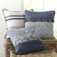 three pillows sitting on top of a wicker basket