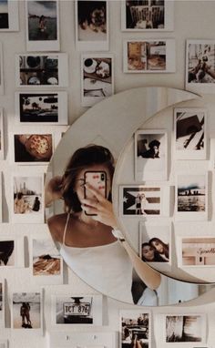 a woman taking a selfie in front of a mirror with pictures on the wall