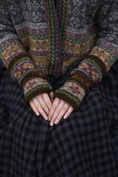 a woman with her hands in the pockets of her pants and sweater, sitting down