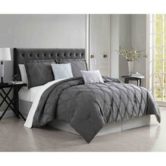 a bed with grey and white comforters in a room