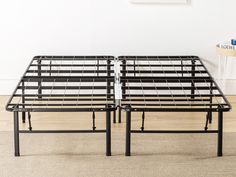 two metal bed frames sitting next to each other on the floor in front of a white wall