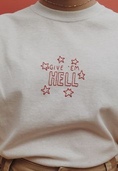 a person wearing a white shirt that says give em hell with stars on the chest