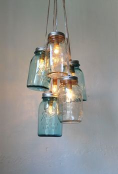 mason jar chandelier hanging from the ceiling with lights in it and jars on top