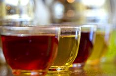 three glasses filled with liquid sitting on top of a table