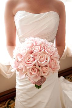 a bride holding a bouquet of pink roses in front of her wedding gown and nail polish