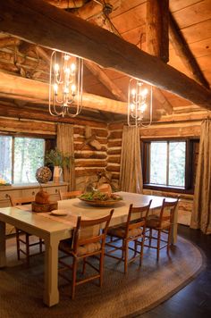 a dining room table and chairs in a log cabin with lights hanging from the ceiling