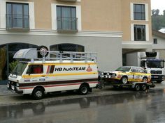 an ambulance towing a tow truck behind it on a city street in front of a building