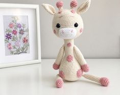 a crocheted giraffe is sitting next to a framed photo and some flowers